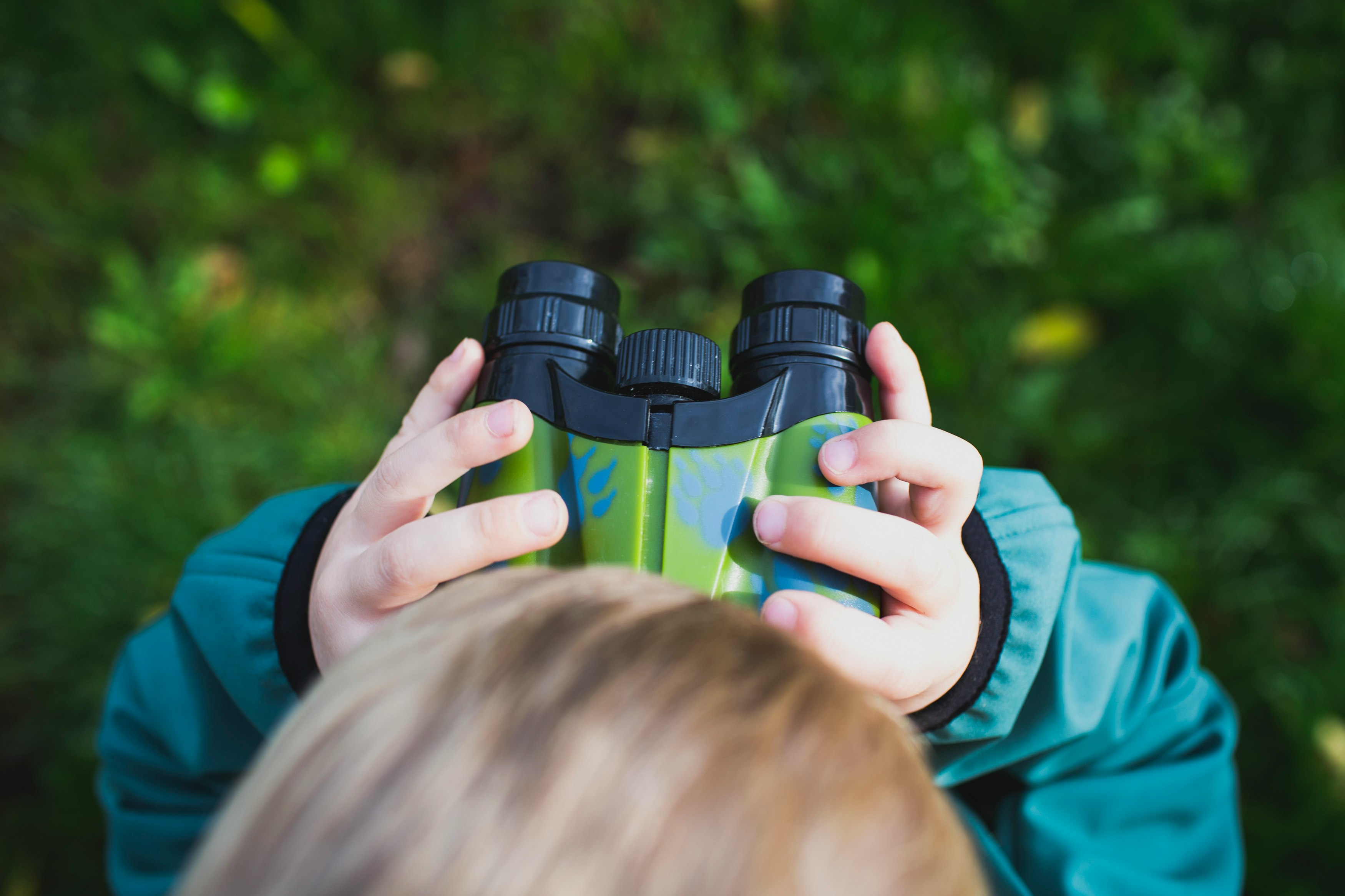 boy in green shirt holding binoculars